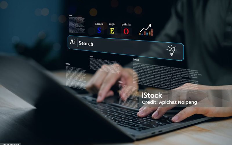 Handen typen op een laptop met een AI-zoekmachine en SEO-elementen die boven het scherm zweven